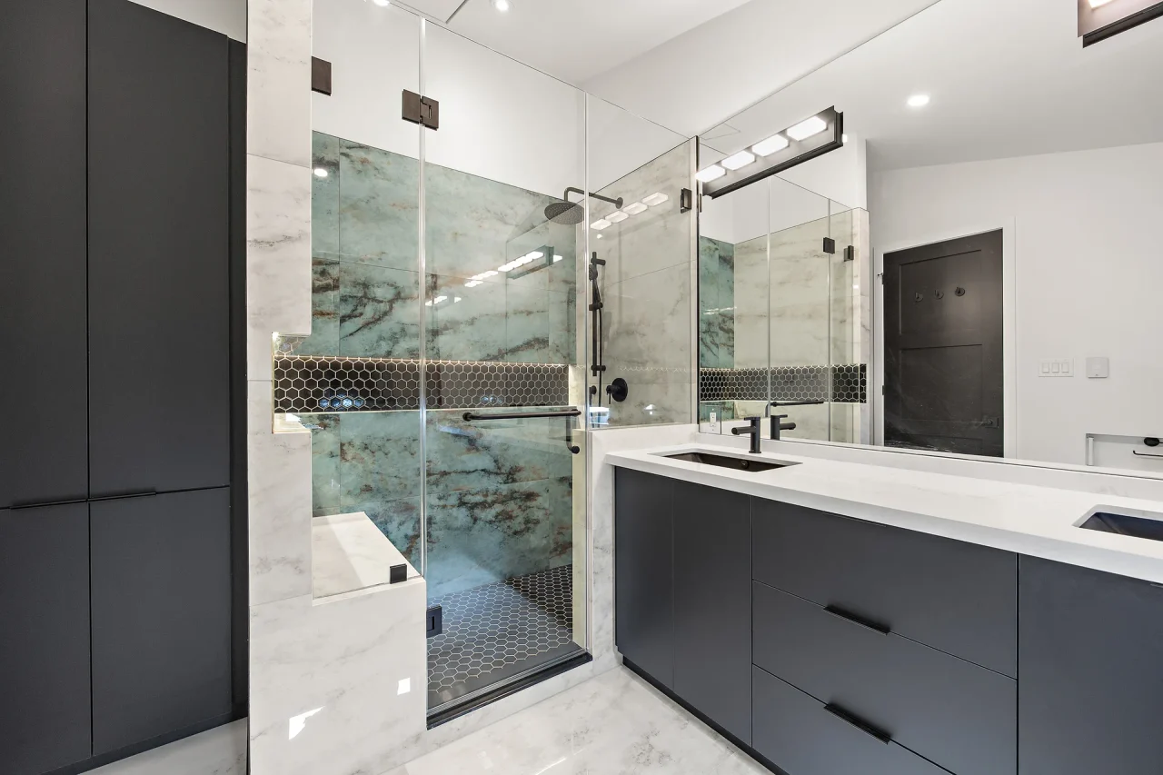 Finished bathroom with glass shower, double vanity and dark cabinetry