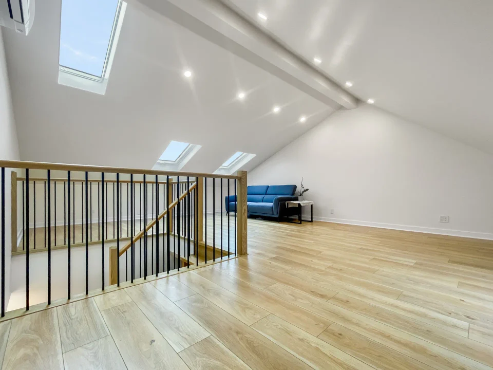 Finished townhouse attic with skylights, stair railing and hardwood flooring