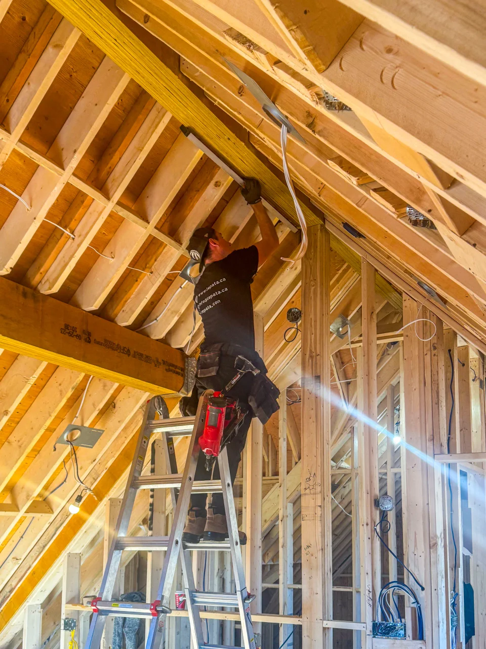Carpenter installing roof framing inside a residential attic